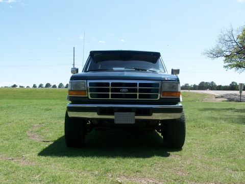 1995 Ford C-350 (Centurion Conversions) - Frontal view of a dark blue Ford truck with a chrome grille and large tires.
