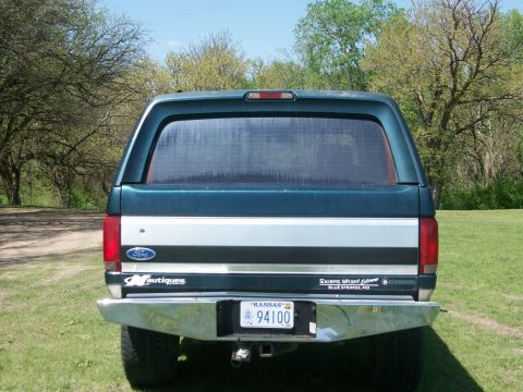 1995 Ford C-350 (Centurion Conversions) - This Ford truck features a camper shell and a custom bumper, seen from the rear.
