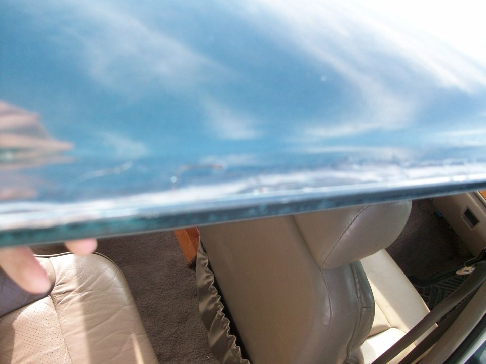 Close-up of glass pane edge above a tan leather car interior