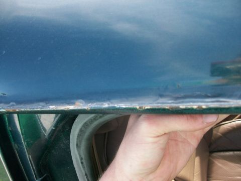 1995 Ford C-350 (Centurion Conversions) - Close-up of a car door's edge and seal, with a hand holding it open.