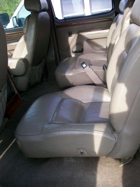 1995 Ford C-350 (Centurion Conversions) - Interior view of a van's passenger seating area, showing multiple rows of tan leather seats.