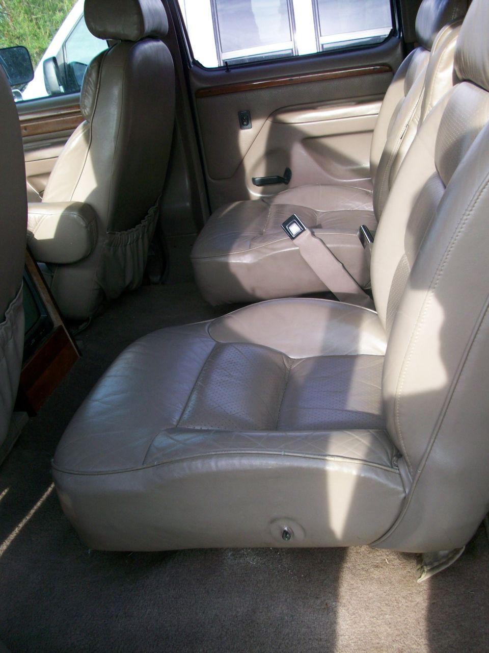 Tan leather captain's chairs and bench seats in a van interior, viewed from the side