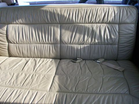 1995 Ford C-350 (Centurion Conversions) - Interior view of a beige leather bench seat with visible seatbelts and quilted detailing.