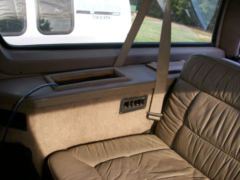 1995 Ford C-350 (Centurion Conversions) - Interior view of a van, showing tan leather seats and a seatbelt. Text on exterior window is visible.