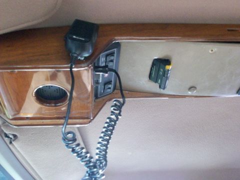 1995 Ford C-350 (Centurion Conversions) - Overhead console detail inside a truck cab, with a wood-grain trim panel holding a small speaker grille, rocker switches, and a black Midla…
