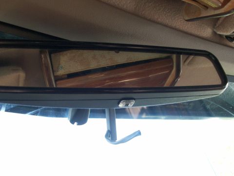 1995 Ford C-350 (Centurion Conversions) - Interior view of a wide black rear-view mirror mounted to the windshield of a truck, with the tan headliner above and the mirror reflecting…