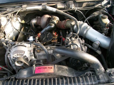 1995 Ford C-350 (Centurion Conversions) - Close-up view of a vehicle's engine bay, showing various components and a warning label.