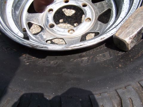 1990 Ford Bronco - A close-up shows a tire and wheel assembly with a sledgehammer nearby.