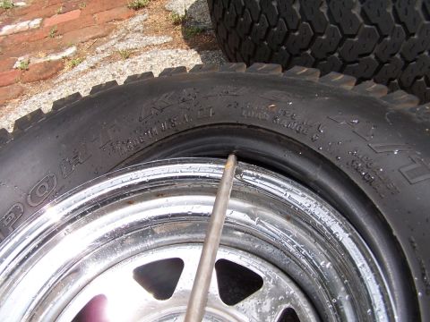 1990 Ford Bronco - A close-up view of a tire mounted on a shiny chrome rim, with text visible on the tire's sidewall.