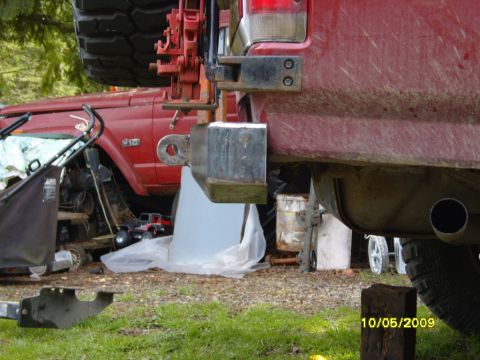 1989 Ford Bronco - The rear of a red SUV shows a custom bumper and tow hitch, with another vehicle in the background.
