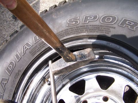 1990 Ford Bronco - A hammer is used to strike a tire valve stem on a chrome rim.