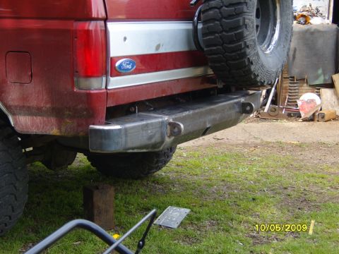 1989 Ford Bronco - Rear view of a red Ford Bronco, showing its aftermarket bumper and spare tire. The Ford logo is visible on the tailgate.
