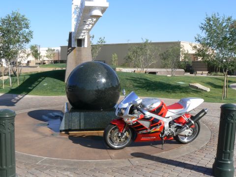 1978 Ford Bronco - A red and silver Honda motorcycle is parked in front of a large black sphere sculpture on a sunny day.