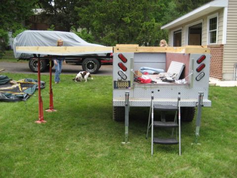 1996 Ford Bronco - Trailer and tarp-covered vehicle in a grassy yard with a dog nearby.