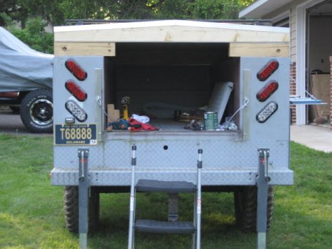1996 Ford Bronco - Rear view of a truck bed with a ladder and tools inside, with another vehicle covered in a tarp to the left.