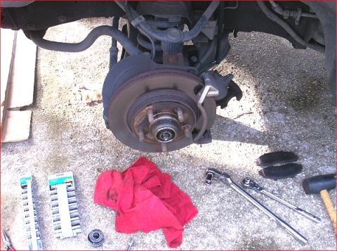 2007 Ford Mustang - Tools and a front brake assembly are laid out on the ground, suggesting a repair or maintenance task.