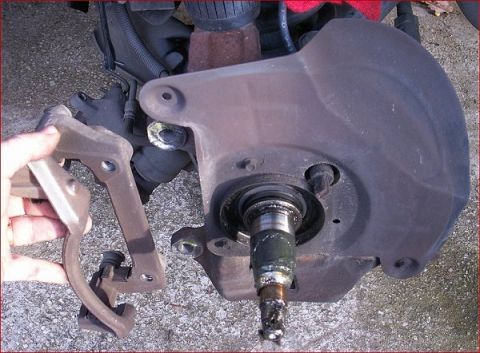 2007 Ford Mustang - Close-up of a vehicle's brake caliper and rotor assembly, with a hand holding the caliper.