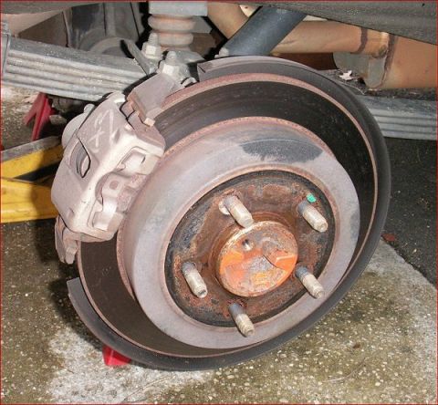 2007 Ford Mustang - Close-up view of a rear brake rotor and caliper, showing signs of wear and rust.