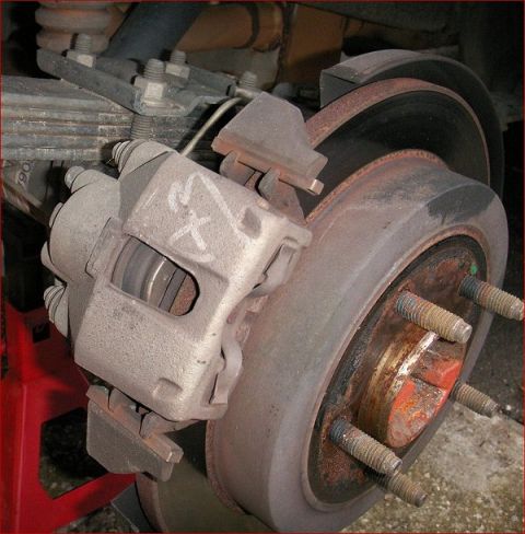 2007 Ford Mustang - Rear brake caliper and rotor assembly, showing signs of rust and wear.
