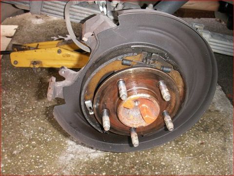2007 Ford Mustang - The rear brake assembly of a vehicle is shown, with the drum removed to expose the brake shoes and hardware.