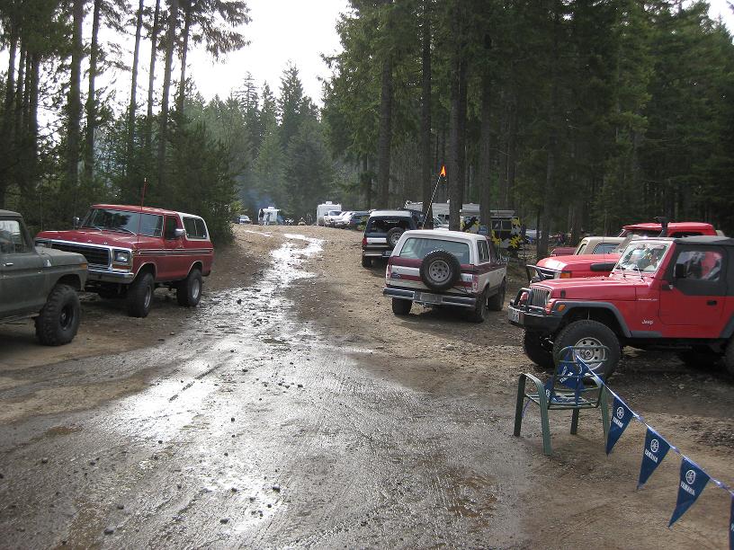 Lineup of lifted trucks and Jeeps on a muddy forest road
