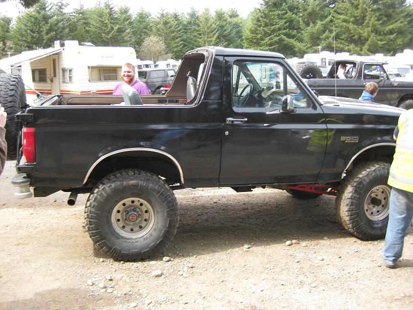 Side view of black lifted Ford Bronco with top removed at off-road event