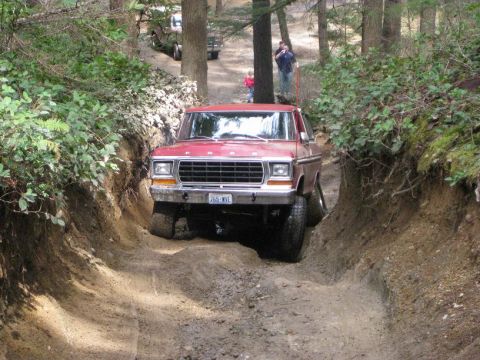 1992 Ford Bronco - A red Ford truck navigates a narrow dirt path with trees on either side.