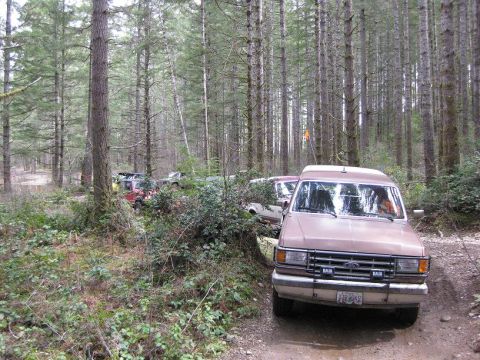 1992 Ford Bronco - Several vehicles are parked on a wooded trail, with a brown van in the foreground.