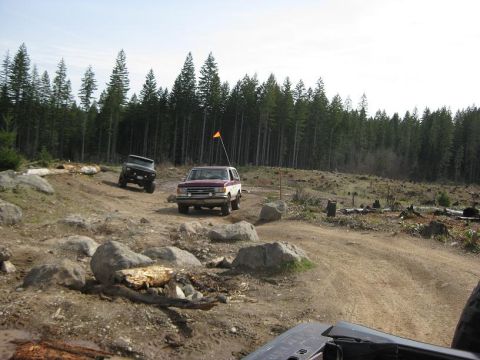 1992 Ford Bronco - Two SUVs navigate a rocky, wooded off-road course.