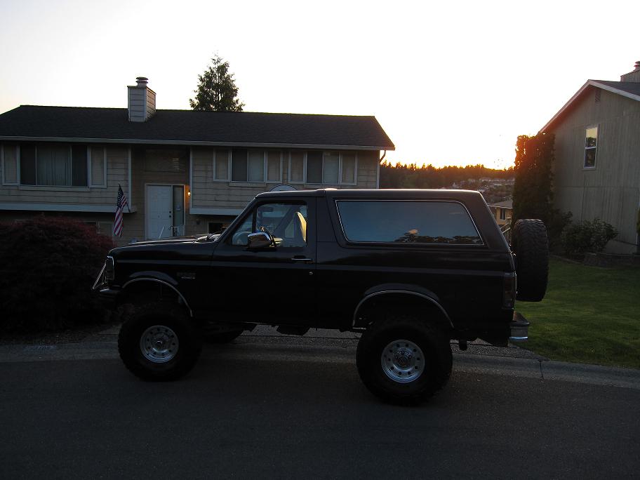 Black 1992 Ford Bronco parked on street, lifted suspension, spare tire on rear door