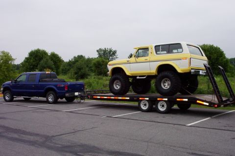 1978 Ford Bronco - A lifted 1978 Ford Bronco is transported on a trailer pulled by a blue pickup truck.