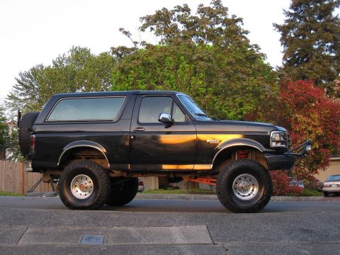 1992 Ford Bronco - A black 1992 Ford Bronco with a lifted suspension and off-road tires is parked on a street.