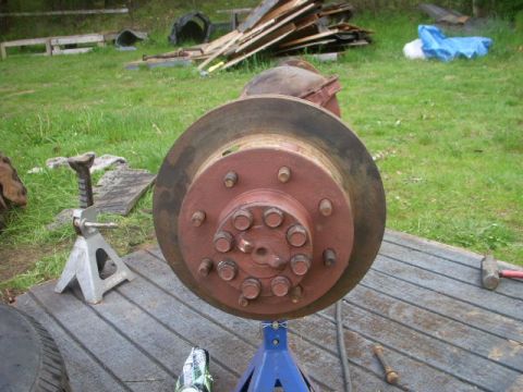 1995 Ford Bronco - A close-up view of a vehicle's axle and brake assembly, supported by jack stands outdoors.