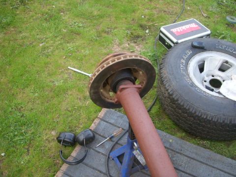 1995 Ford Bronco - A vehicle driveshaft and brake rotor are shown disassembled on a grassy area next to a tire.