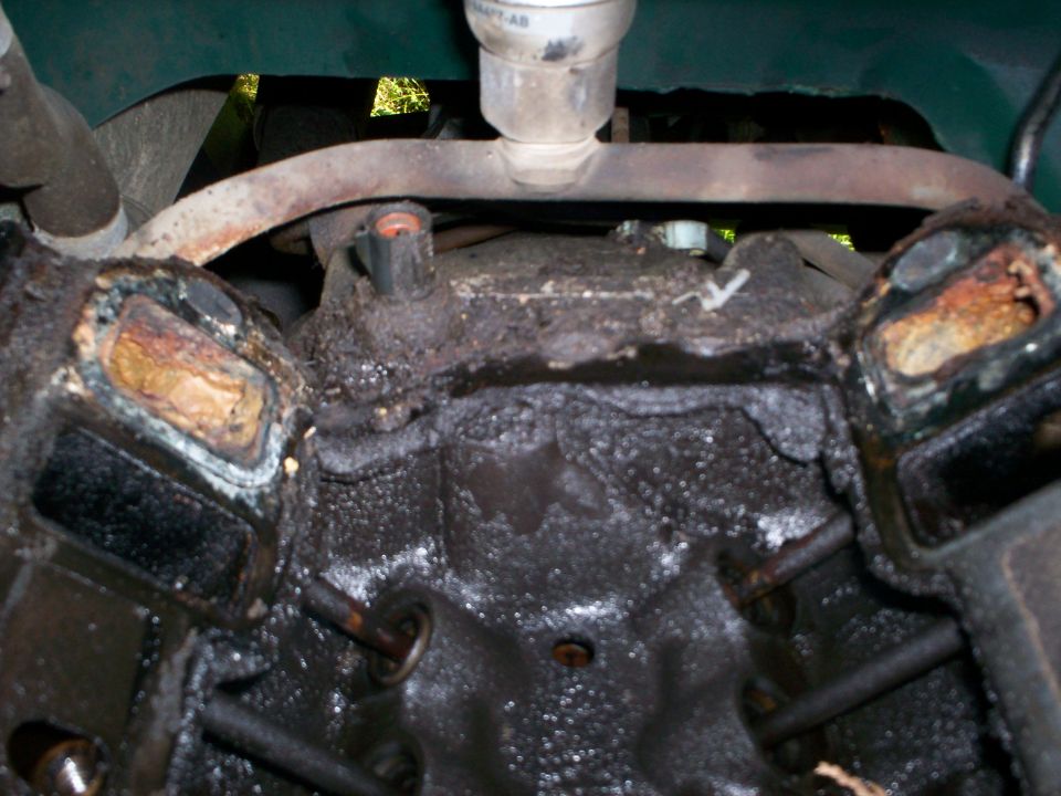Close-up of a dirty engine block showing corroded cylinder heads and internal components