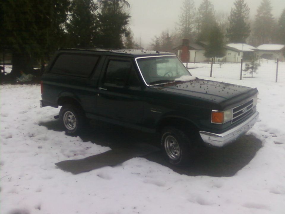 Dark green 1987 Ford Bronco parked in snow, front 3/4 view