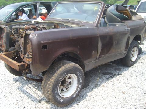 1994 Ford Bronco - This brown convertible SUV is missing its front end and appears to be in a junkyard setting.