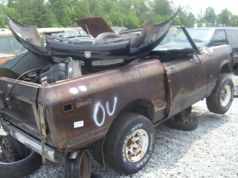 1994 Ford Bronco - Junkyard International Scout II pickup truck with a damaged black bumper resting on its hood.