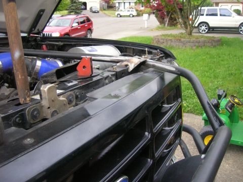 1996 Ford Bronco - The front of a black truck is shown with its hood open, revealing engine components and a custom bar attached to the grille.