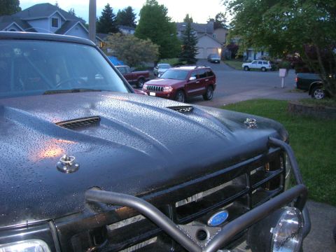 1996 Ford Bronco - Close-up of a black SUV's hood covered in raindrops, with a brush guard visible.