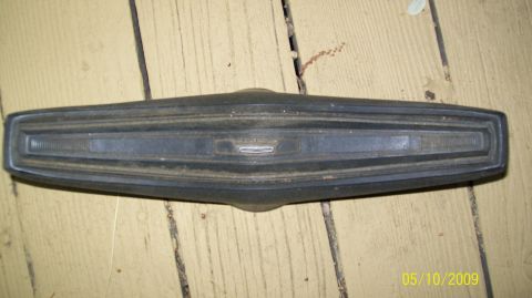 1972 Ford Ranchero - A detached car emblem and trim piece lies on a weathered wooden surface.