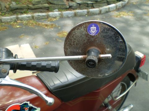 1981 Garelli Rally Sport - Close-up of a weathered motorcycle mirror a crest sticker, likely from a school or organization.