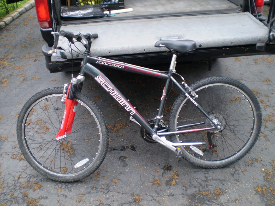 Schwinn Ranger mountain bike with red front fork, parked next to a pickup truck bed