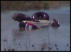 1990 Ford Bronco - An off-road vehicle is stuck in the water, with only its tires and part of the body visible.