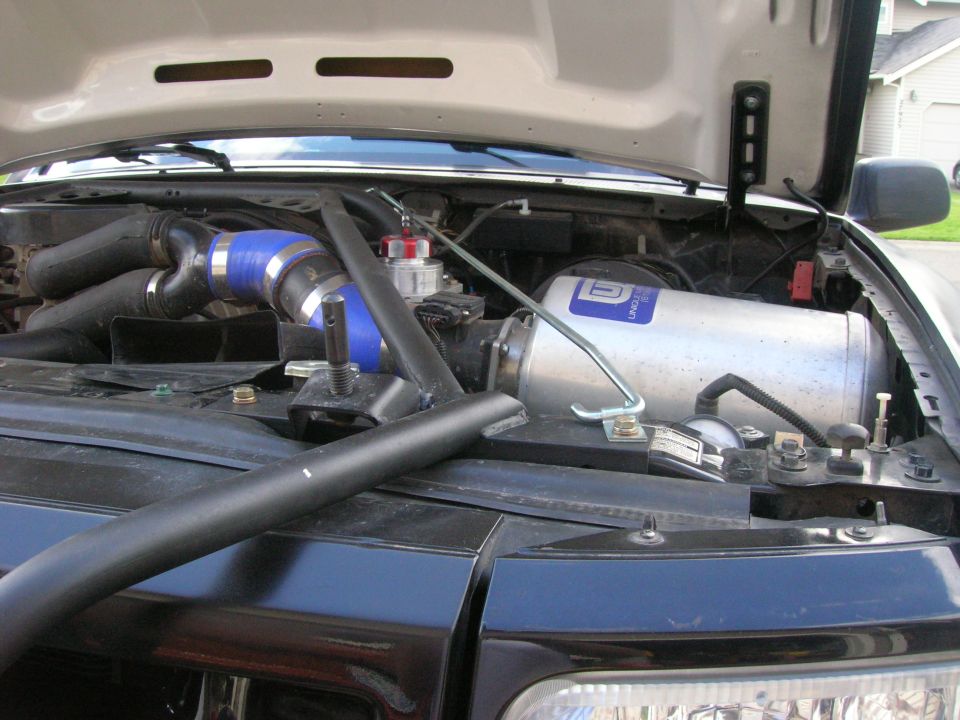 Engine bay with polished canister on inner fender, blue silicone coupler and chrome intake tube