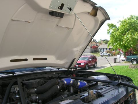 1996 Ford Bronco - View of the engine bay with the hood raised, revealing custom turbocharger piping and other engine parts.
