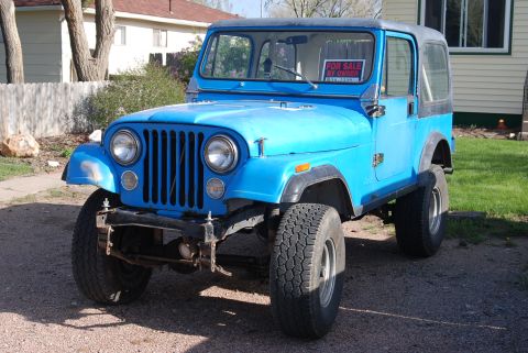 1981 Jeep CJ7 - A blue Jeep CJ is parked in a driveway with a 'For Sale By Owner' sign visible in the windshield.
