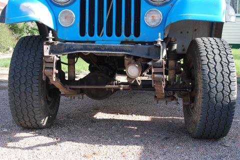 1981 Jeep CJ7 - Front view of a blue Jeep CJ7, showing its axle, leaf spring suspension, and tires with visible rust.