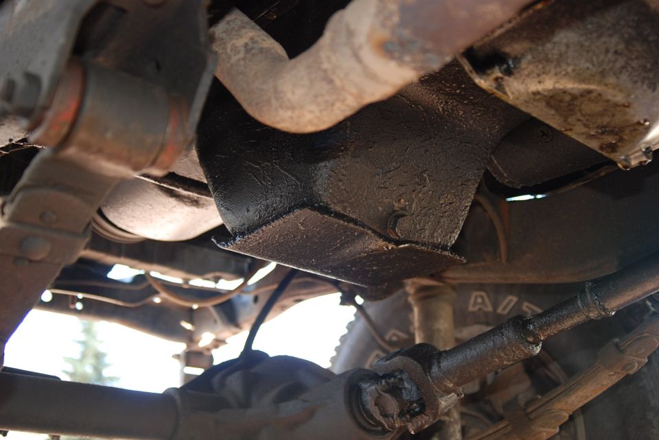 Underbody view of vehicle with skid plate and suspension parts. "SUPERMOTORS.NET" visible