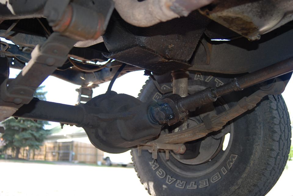 Underside view of a Jeep's front axle, driveshaft, and leaf springs